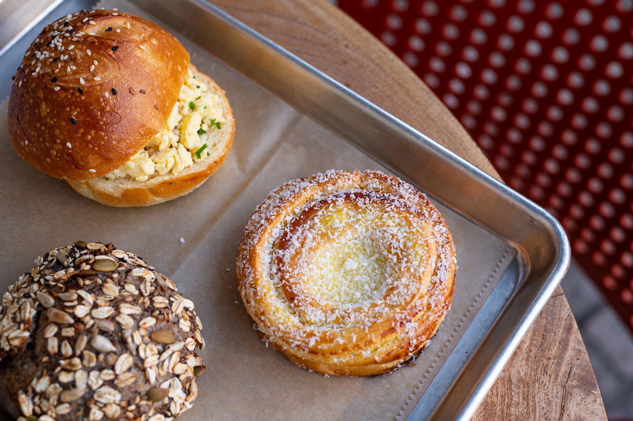 A tray with an egg sandwich, seeded bread, and a pastry